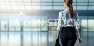 Flight attendant walking on the airport hall viewed from behind and with the hair with a pony tail