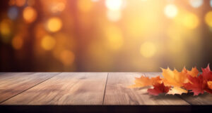 A wooden table decorated with some leaves and a blured background in the style of a mockup