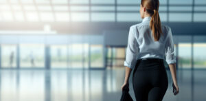 Flight attendant walking on the airport hall viewed from behind and with the hair with a pony tail