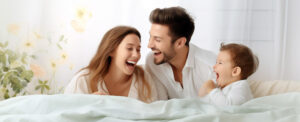 Happy couple with their child laughing in the morning over a bed